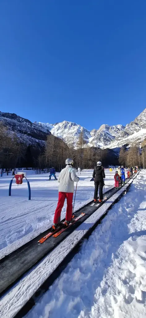 Bambini e principianti in allenamento al campo scuola sci di Macugnaga, con maestri esperti e un paesaggio innevato suggestivo.