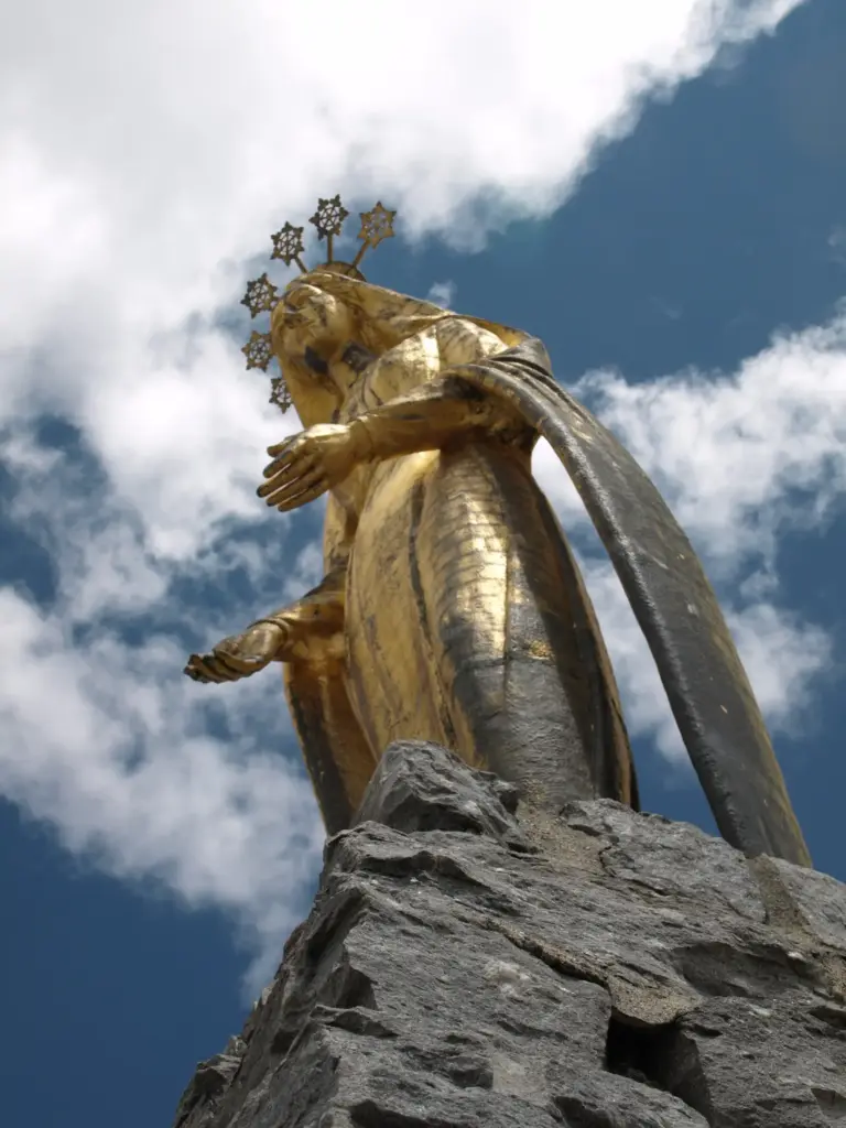 Primo piano della statua della Madonna della Neve al Passo del Monte Moro, con vista sulle montagne di Macugnaga, Monte Rosa.