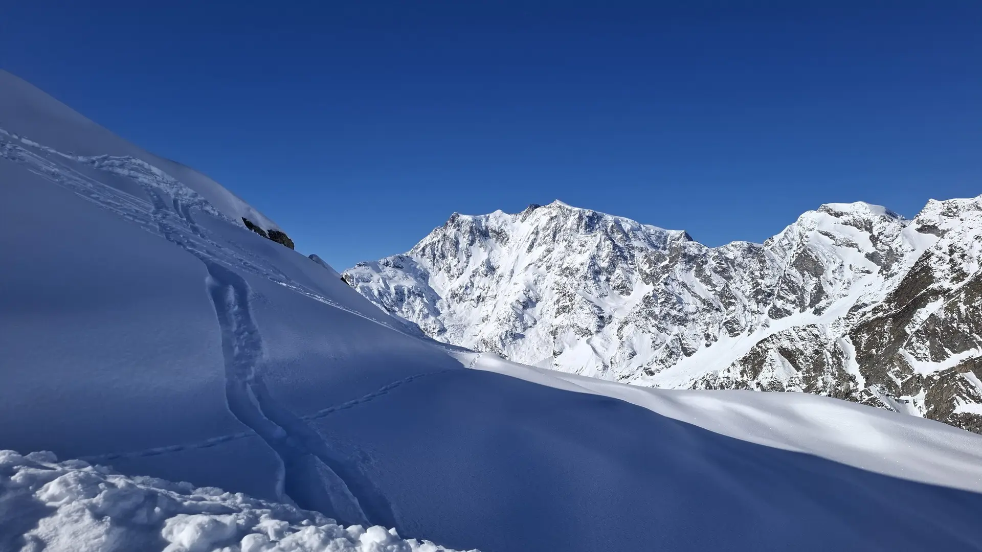 a snow covered mountain with a trail in the middle