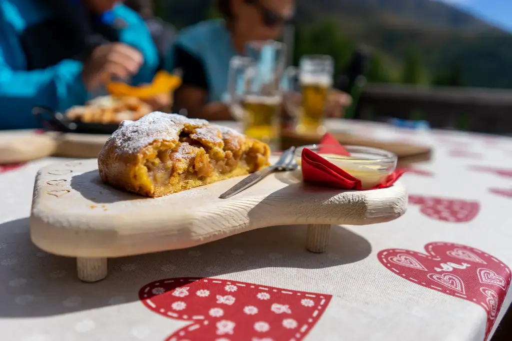 Tavola apparecchiata per una cena in montagna, con piatti tipici e vista sulle cime alpine di Macugnaga